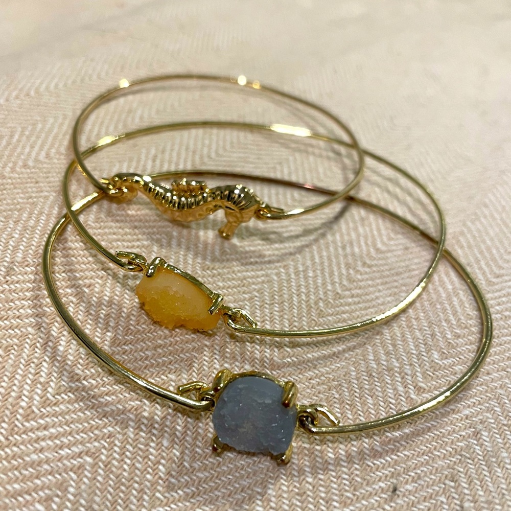 Set of 3 gold bangles with seahorse and stones.